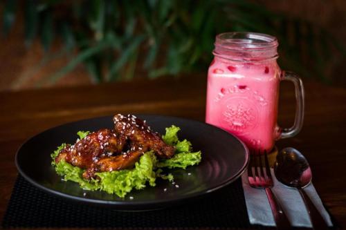 a plate of food with meat and lettuce and a pink drink at Hadi Poetra Hotel in Kuta
