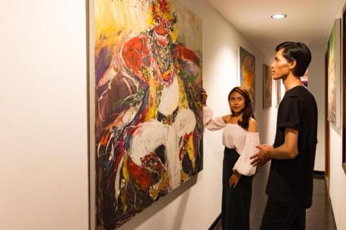 a man and a woman looking at a painting at Hadi Poetra Hotel in Kuta