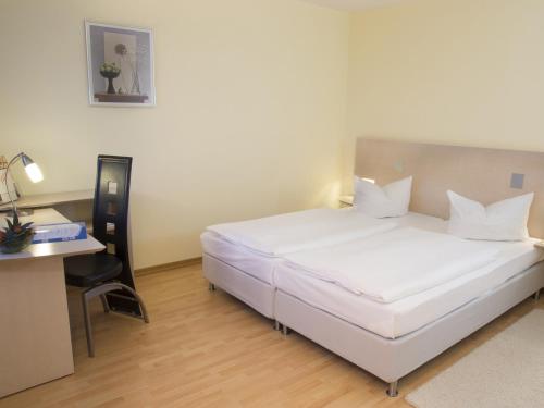 a large white bed in a room with a desk at Atlanta Boardinghouse Leipzig in Leipzig