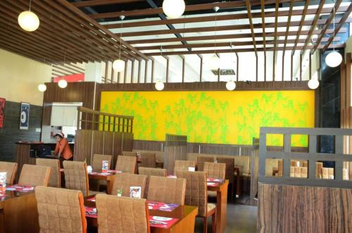 a dining room with tables and chairs and a yellow wall at Asialink Premier in Karawang