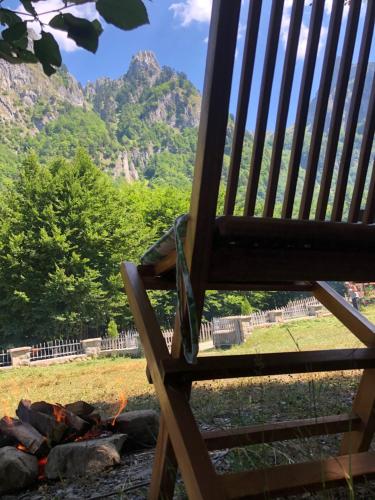 a bench with a camp fire and mountains in the background at Prokletije Vucetic sobe in Dolja
