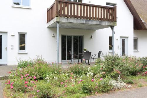 a balcony on a house with pink flowers at Fewo 2 Stueven im Reetdachhaus Fewo cc in Kolpinsee