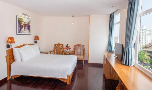 a bedroom with a bed and a desk with a television at Romance Hotel in Hue