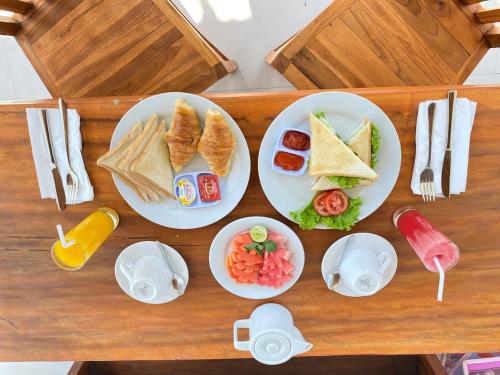 De Casa Ananda Nusa Penida في نوسا بينيدا: طاولة خشبية عليها أطباق طعام