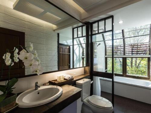 a bathroom with a sink and a toilet and a tub at Doltara Boutique Resort in Chiang Mai