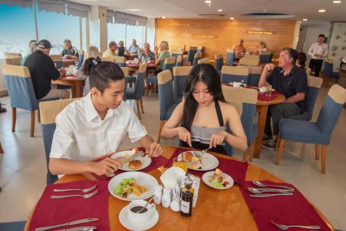 a man and woman sitting at a table eating food at Romance Hotel in Hue