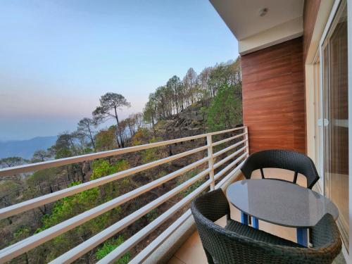 a balcony with a table and chairs and a view at Wonder Hill Kasauli in Kasauli