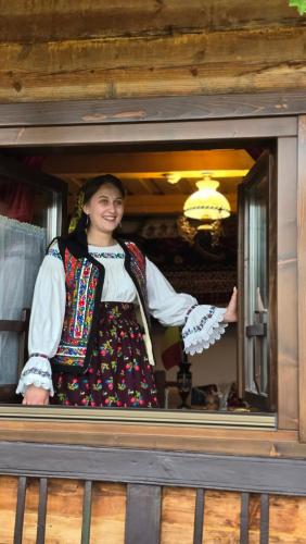 a woman is standing in a window at Casuta din Cotroape - Maramureș in Săcel