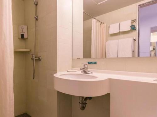 a bathroom with a white sink and a mirror at Jinjiang Inn Xi'an Dayan Tower Xiaozhai Metro Station in Xi'an