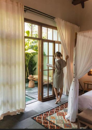 a woman is looking out of a bedroom door at La Reserve 1785 Canggu Beach - Adults Only in Canggu