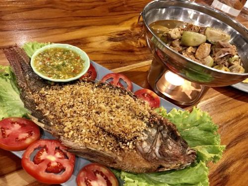 a plate of food with a fish and tomatoes on a table at The River Life Resort in Ban Kaeng Raboet