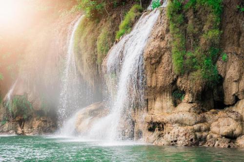 a waterfall on the side of a rocky cliff at The River Life Resort in Ban Kaeng Raboet