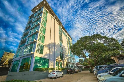 a tall building with cars parked in front of it at Phuglong Hotel in Phayao