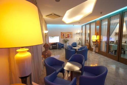une salle d'attente avec des chaises bleues et une lampe jaune dans l'établissement Hotel Medusa, à Sottomarina