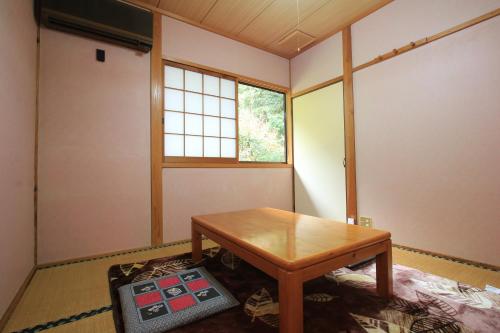 a room with a wooden table and a window at 民宿ひろしげ in Izuno
