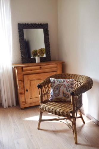 une chaise en osier avec un oreiller et un miroir dans l'établissement le loft de Nana, à Osthouse