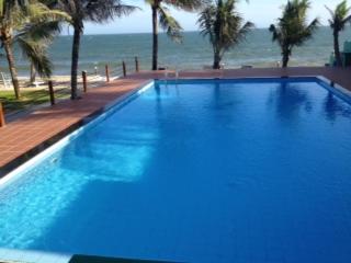 a large swimming pool with the ocean in the background at Hiep Hoa Resort in Mui Ne