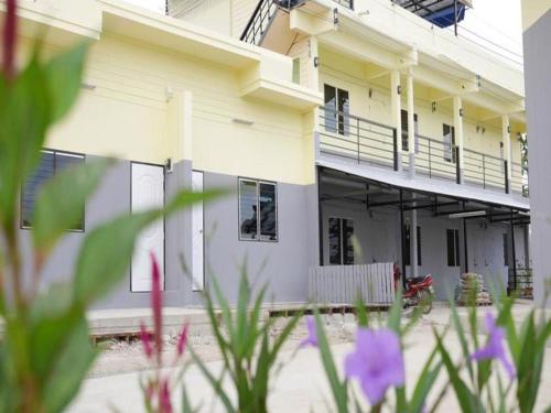 a white building with purple flowers in front of it at OYO 769 Ban Thassanee in Chiang Mai