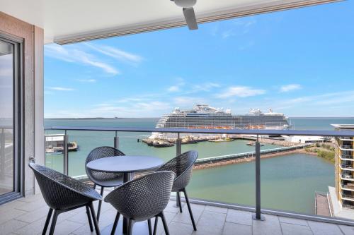 a balcony with a table and chairs and a cruise ship at Serenity Sea La Vie - 3brm Penthouse at Darwin Waterfront in Darwin