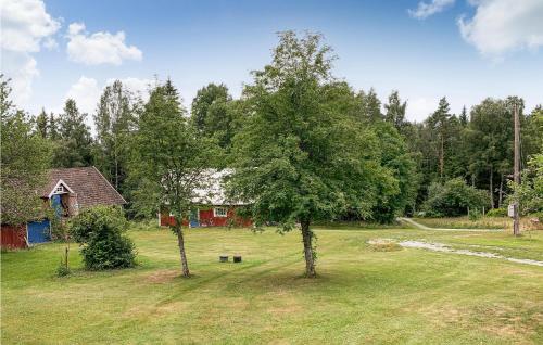 a tree in the middle of a field with a house at 3 Bedroom Awesome Home In Vrigstad in Vrigstad