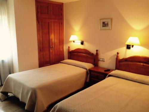 Habitación de hotel con 2 camas y 2 lámparas en Hostal Nicolás, en Medinaceli