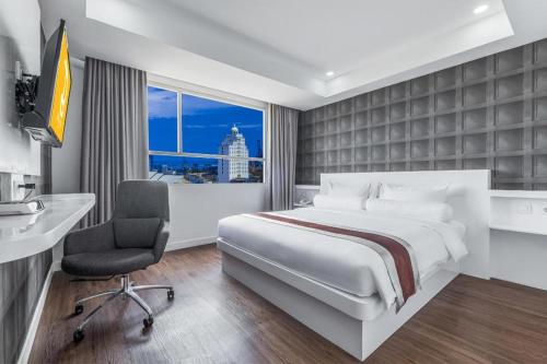 a hotel room with a bed and a desk and a window at Royal Bay Hotel Makassar in Makassar