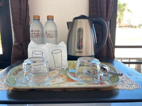 Una bandeja con una tetera y vasos sobre una mesa. en Thongsuk Mini Resort, en Pran Buri