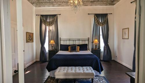 a bedroom with a bed and two windows at The 1890 Freeman House in Galveston