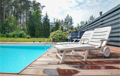two white chairs sitting on a deck next to a swimming pool at Holiday Home Høgevej Kolind Vi in Kolind