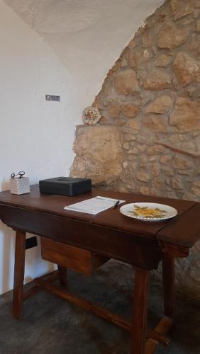 a wooden table with a plate on it next to a stone wall at B&b Diamante and home restaurant in Trentinara