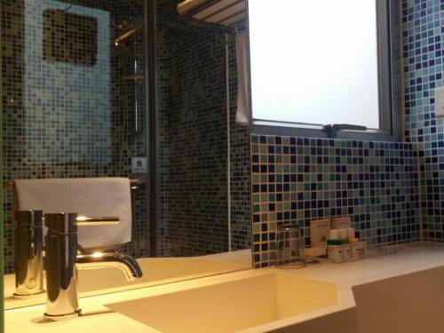 a bathroom with a sink and a window and a mirror at Acesite Knutsford Hotel in Hong Kong