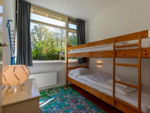 ein Schlafzimmer mit zwei Etagenbetten und einem Fenster in der Unterkunft Bungalow near Dutch Beach with Garden in Oostkapelle