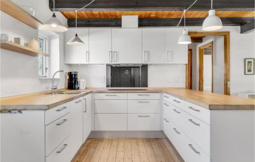 a kitchen with white cabinets and a wooden floor at 3 Bedroom Cozy Home In Bindslev in Bindslev