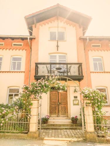 ein Haus mit einer Holztür und einem Balkon in der Unterkunft Dorfschänke DEGGENDORF Hotel & Apartmenthaus in Deggendorf