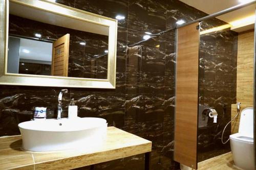 ein Badezimmer mit Waschbecken, Spiegel und Toilette in der Unterkunft Prinn Hotel in Ban Thai Wat Khot