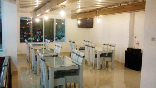 a dining room with tables and chairs and a television at Mitra Hotel Yogyakarta in Yogyakarta