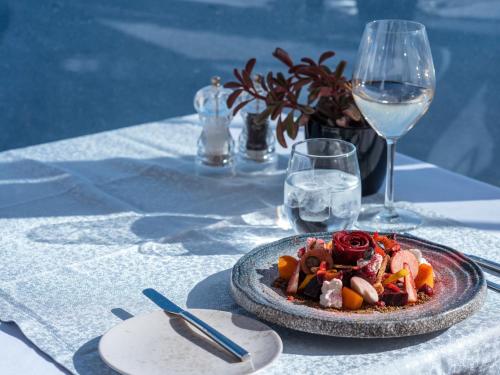 a plate of food on a table with a glass of wine at Santorini Secret Suites & Spa, Small Luxury Hotels of the World in Oia