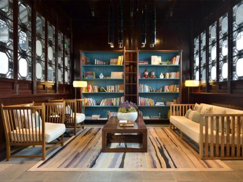a living room with a couch and chairs and bookshelves at Blossom House Suzhou Tanhuafu in Suzhou