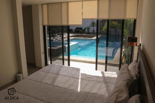 a bedroom with a bed and a swimming pool at ALDEA Luxury villas & suites in San Martín de las Pirámides