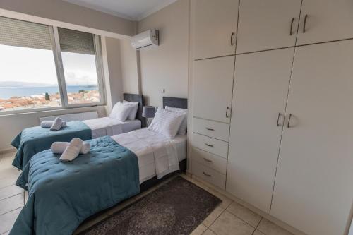 a bedroom with two beds and a large window at ΑμφιΘΕΑ! στη ΝΑΥΠΑΚΤΟ ! in Nafpaktos