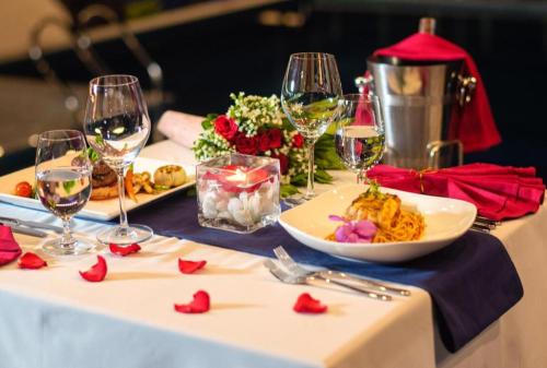 a table with wine glasses and a plate of food at Le Pavillon Hoi An Paradise Hotel & Spa in Hoi An
