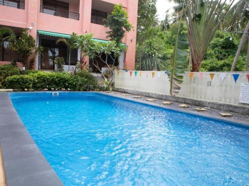 a large blue swimming pool in front of a building at OYO 567 U Residence in Ban Lamai