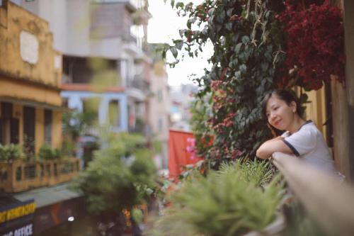 a young girl sitting on a ledge near flowers at Hanoi Win Hotel & Travel in Hanoi