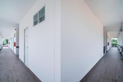 an empty hallway of a building with white walls at Super OYO 662 Malee Bunga Hotel in Si Racha
