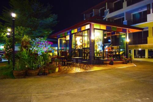 a building with tables and chairs and plants at night at Nantharom Hotel and Restaurant in Chachoengsao