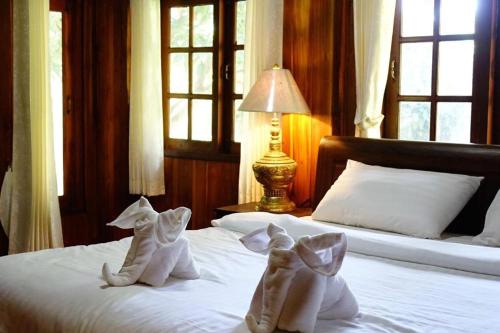 a bedroom with two beds with white socks and a lamp at Capital O923 Elephant at Baan Tawai in Bān Sawan