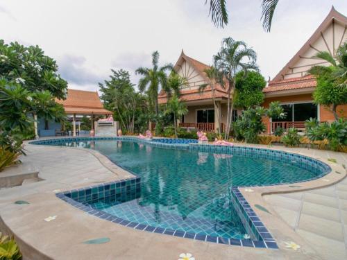 a swimming pool in front of a house at CAPITAL O961 Baan Dow Chompoo Resort in Hua Hin
