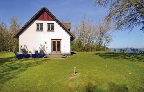 a white house on a green field with chairs at Venøhus in Venø By