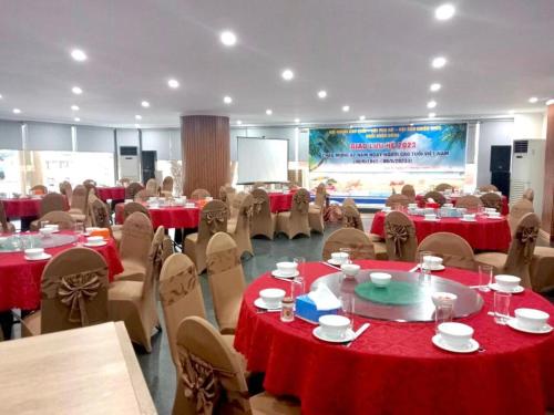 a room filled with tables and chairs with red table cloth at Hon Ngu Hotel Cua Lo Beach in Cửa Lò
