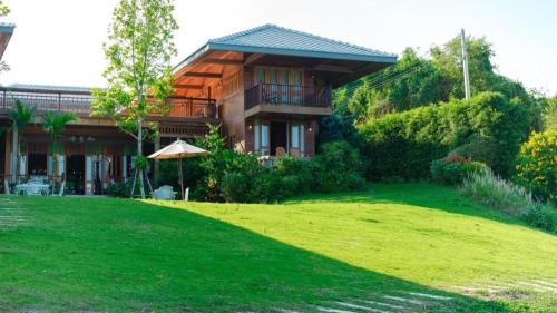 a house with a green lawn in front of it at Burann Bangtanode in Ratchaburi
